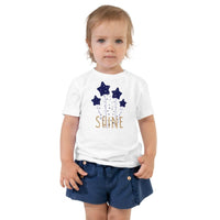 Custom printed toddler tee featuring whimsical stars and the word Shine in elegant gold.