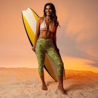 Custom printed Bud Camo Yoga Capri Leggings on a model with a surfboard in a beach setting.